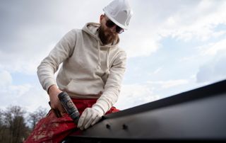 dakwerker-witte-helm-rode-broek-boormachine